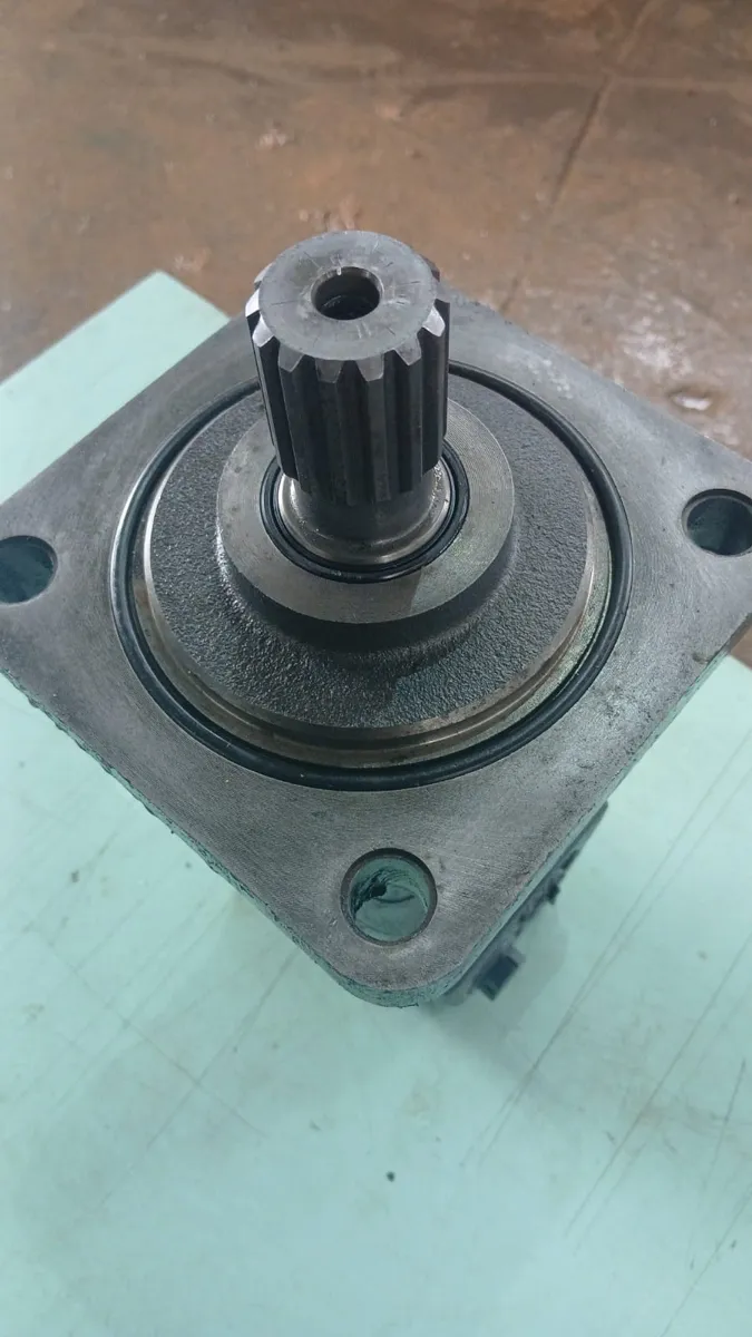 Motor de tração da Bobcat S70 recondicionado, detalhe do eixo estriado e flange