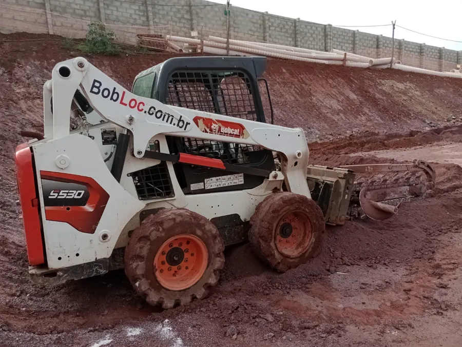 Bobcat com valetadeira abrindo vala em obra